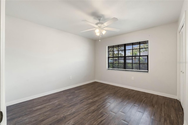 unfurnished room with dark wood-style floors, a ceiling fan, and baseboards