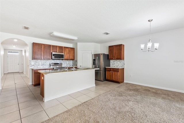 kitchen featuring visible vents, arched walkways, appliances with stainless steel finishes, light countertops, and backsplash