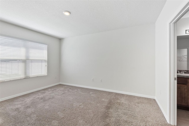 carpeted empty room featuring baseboards and a textured ceiling