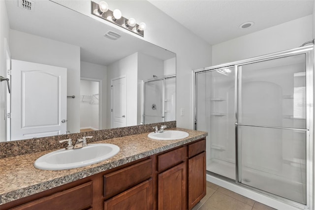 bathroom with tile patterned floors, a sink, visible vents, and a shower stall