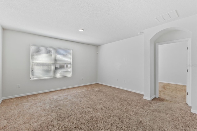 carpeted spare room featuring visible vents, a textured ceiling, and baseboards