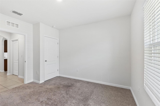 unfurnished bedroom with baseboards, visible vents, and light colored carpet