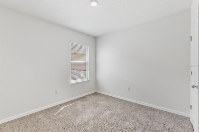 carpeted spare room featuring baseboards