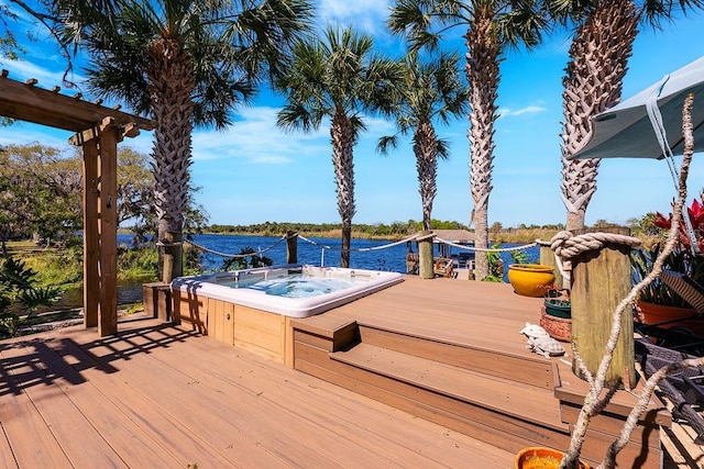 deck featuring an outdoor hot tub and a water view