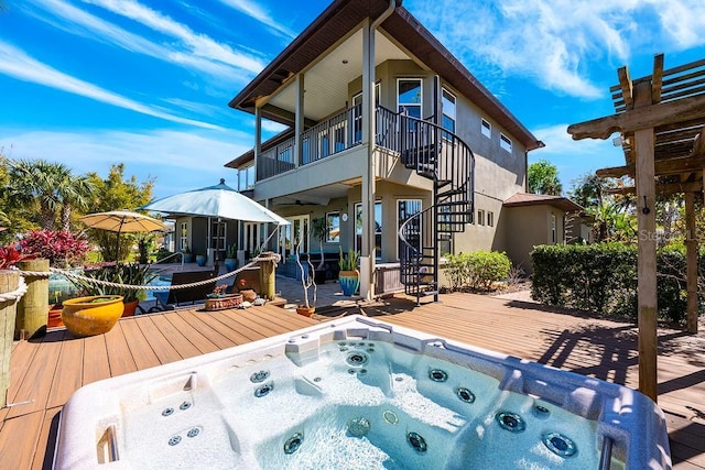 back of property featuring a wooden deck, hot tub deck surround, and stairs