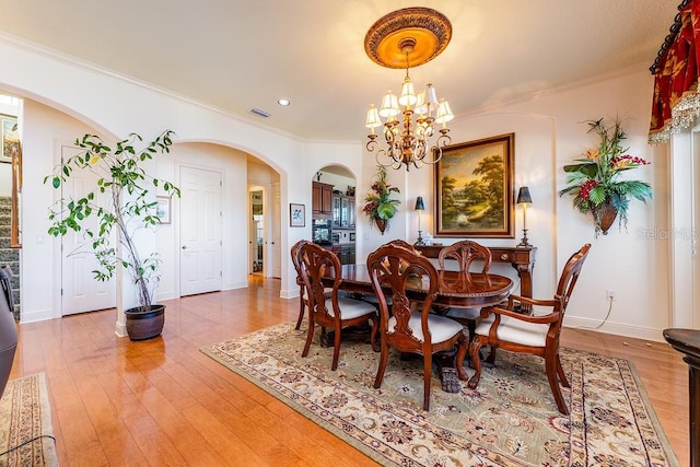 dining room with arched walkways, ornamental molding, and hardwood / wood-style flooring