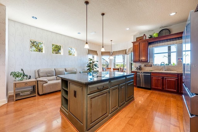 kitchen featuring a sink, stainless steel dishwasher, light wood-style floors, wallpapered walls, and black electric stovetop