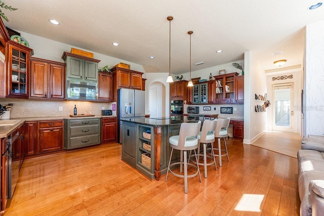 kitchen featuring a kitchen island, a kitchen bar, arched walkways, stainless steel appliances, and open shelves