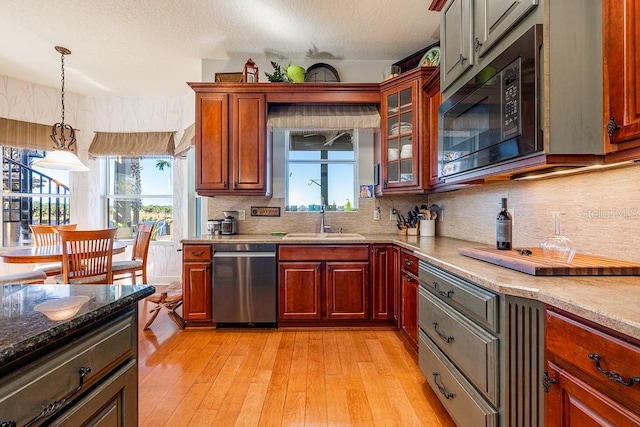 kitchen with black microwave, dishwasher, light wood-style flooring, plenty of natural light, and a sink