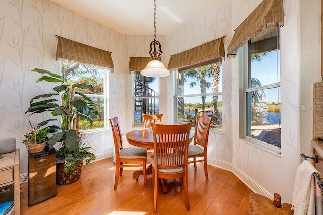 dining space featuring light wood-style flooring, wallpapered walls, and baseboards