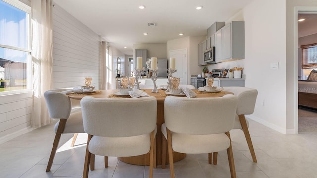 dining space featuring wood walls, light tile patterned floors, visible vents, and recessed lighting