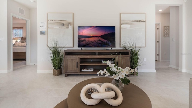 living area featuring light tile patterned floors, visible vents, and baseboards