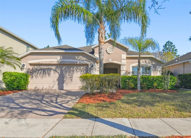 mediterranean / spanish-style home featuring a front yard, decorative driveway, a garage, and stucco siding