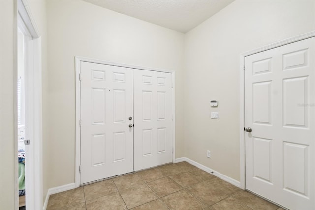 entrance foyer with light tile patterned floors, baseboards, and a textured ceiling