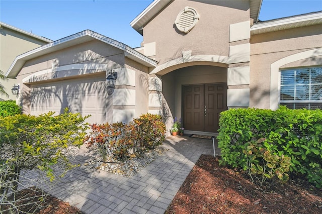 entrance to property featuring a garage and stucco siding