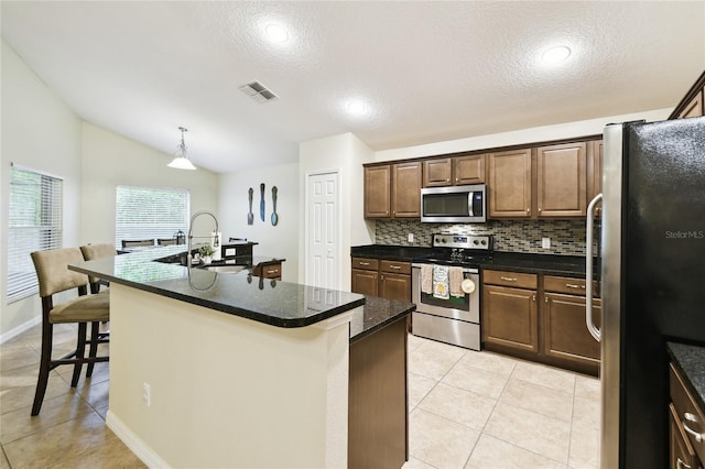 kitchen with visible vents, light tile patterned flooring, a sink, decorative backsplash, and stainless steel appliances