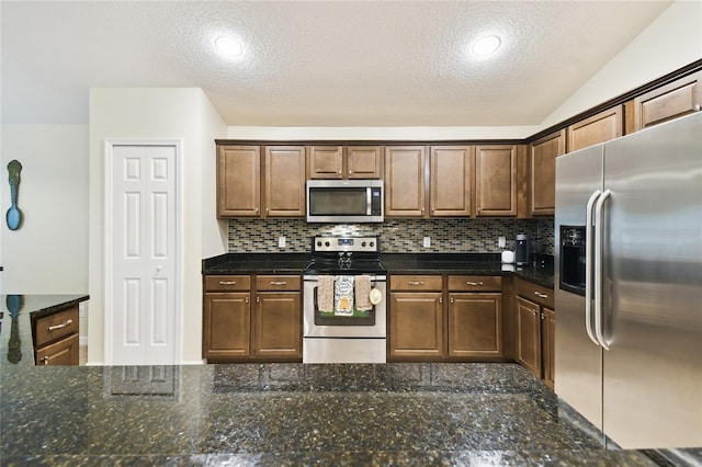 kitchen with decorative backsplash, dark stone countertops, appliances with stainless steel finishes, and a textured ceiling