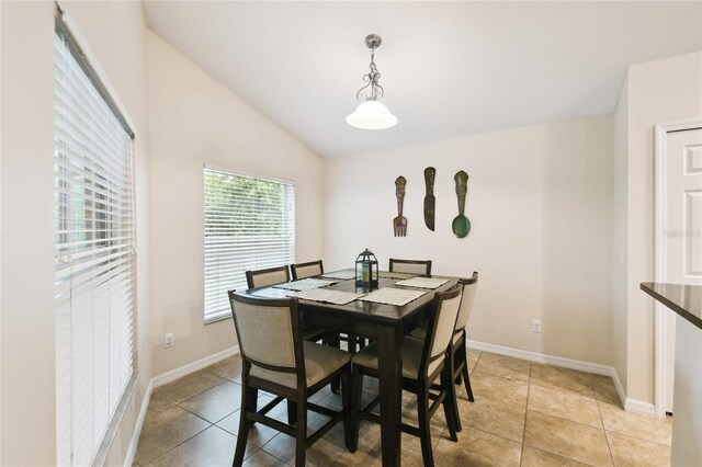 dining space featuring light tile patterned floors, baseboards, and vaulted ceiling