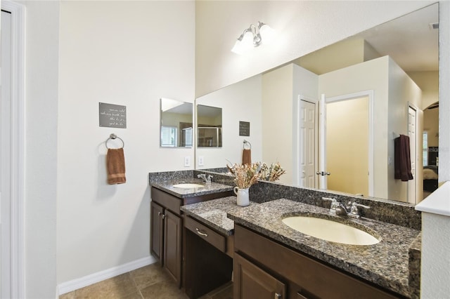 full bath featuring double vanity, baseboards, tile patterned floors, and a sink