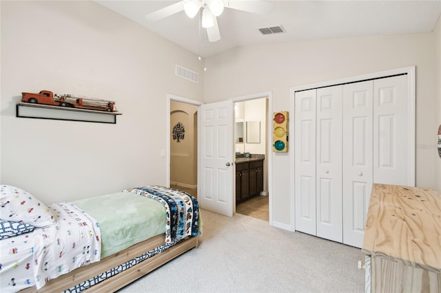 bedroom featuring a closet, visible vents, light colored carpet, and lofted ceiling