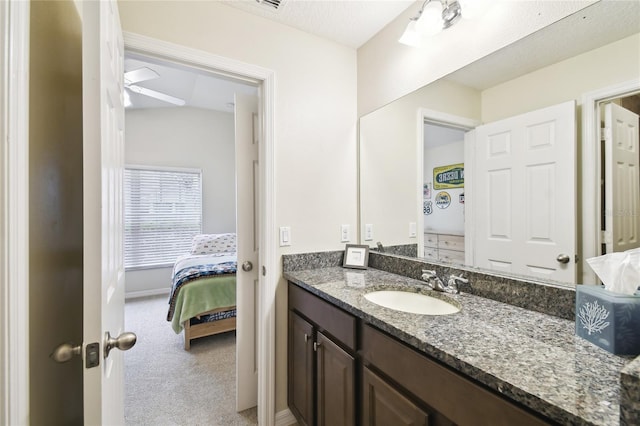 bathroom with baseboards, vanity, ceiling fan, and ensuite bathroom