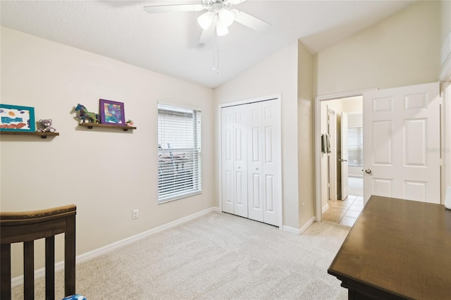 bedroom with a ceiling fan, baseboards, vaulted ceiling, a closet, and light colored carpet