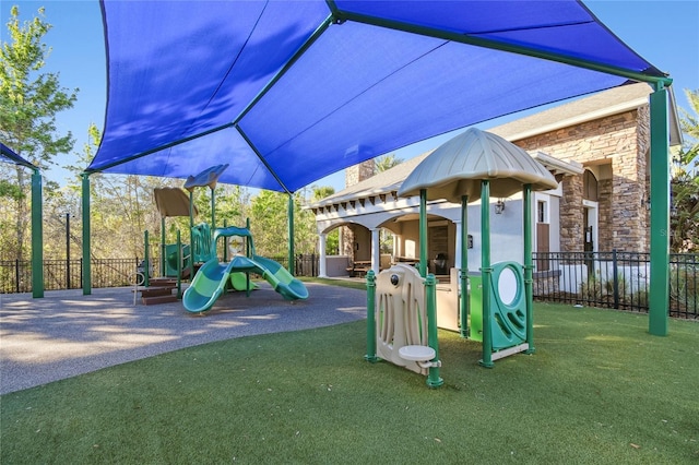 communal playground featuring a yard and fence