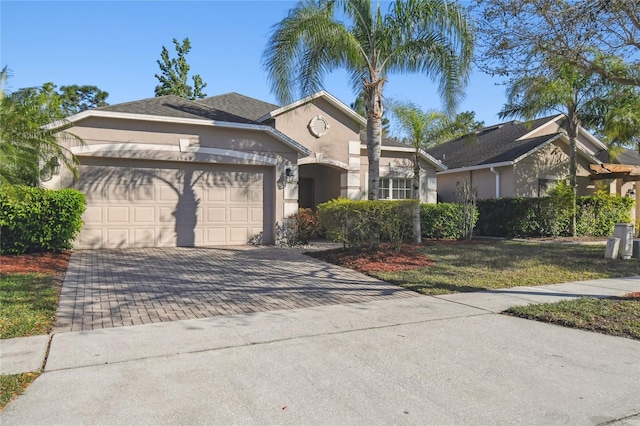 ranch-style home with stucco siding, decorative driveway, a garage, and a front lawn