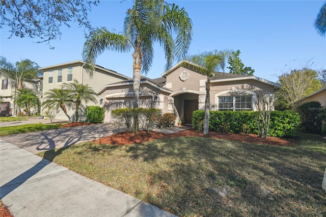 mediterranean / spanish-style home featuring a garage, a front lawn, driveway, and stucco siding