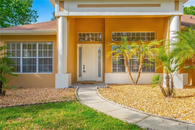 property entrance with roof with shingles and stucco siding