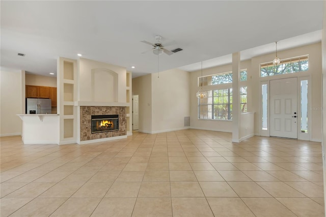 1187 Tadsworth Ter, Lake Mary, FL 32746 - unfurnished living room featuring visible vents, baseboards, ceiling fan, a tiled fireplace, and light tile patterned floors
