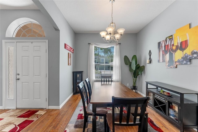 dining space featuring a notable chandelier, baseboards, and light wood-type flooring