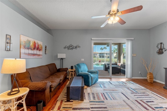 living room with baseboards, a textured ceiling, ceiling fan, and wood finished floors