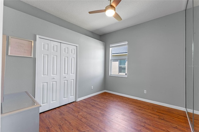 unfurnished bedroom with a closet, ceiling fan, baseboards, and wood finished floors