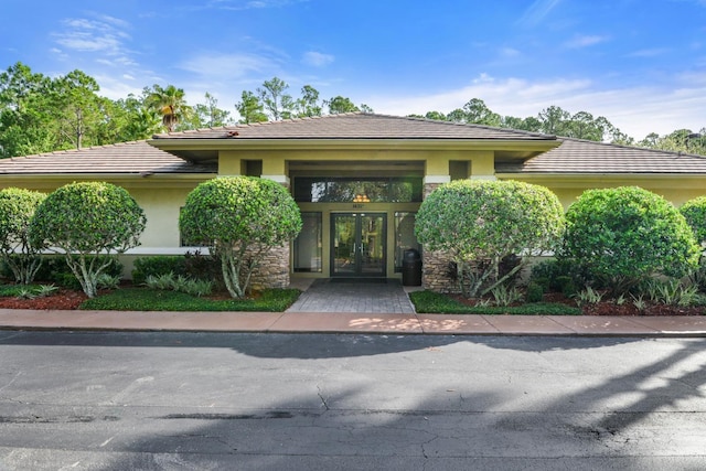 view of front of home featuring a tiled roof, stucco siding, and french doors