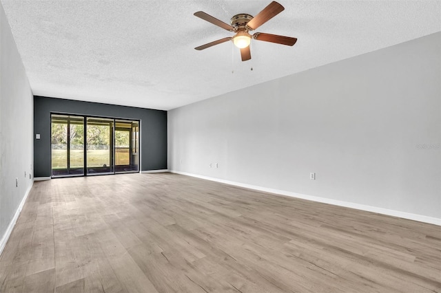 empty room with ceiling fan, light wood-style floors, baseboards, and a textured ceiling