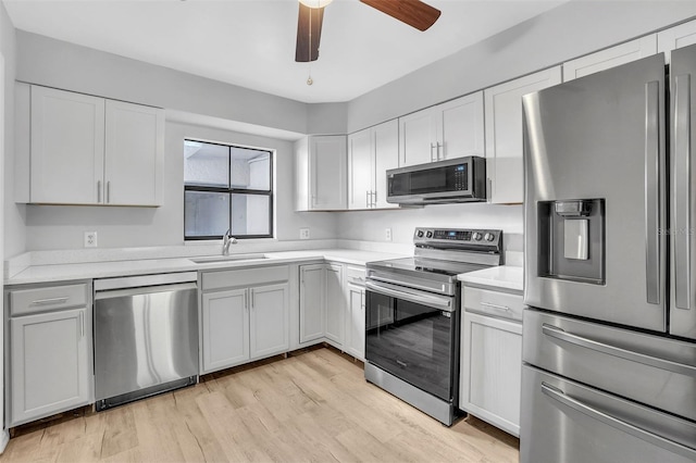 kitchen featuring light countertops, light wood-style floors, appliances with stainless steel finishes, and a sink