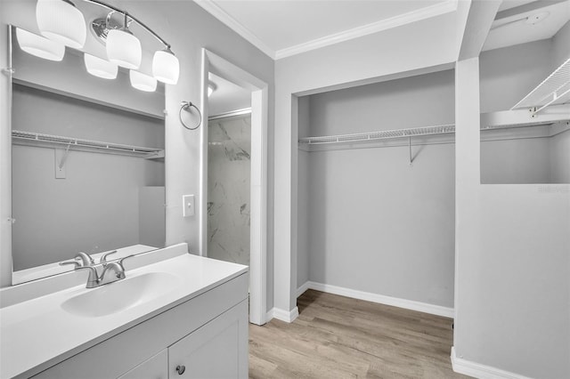 full bathroom featuring a spacious closet, ornamental molding, vanity, and wood finished floors