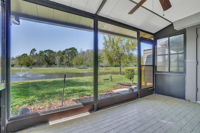 unfurnished sunroom featuring a water view, a healthy amount of sunlight, a ceiling fan, and vaulted ceiling