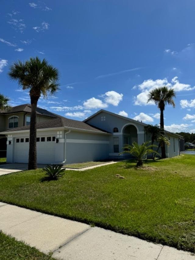 ranch-style home featuring a front yard, concrete driveway, a garage, and stucco siding