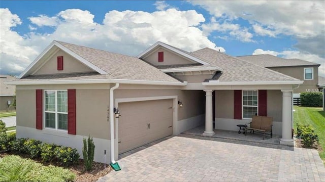 view of front of home with stucco siding, decorative driveway, roof with shingles, covered porch, and a garage