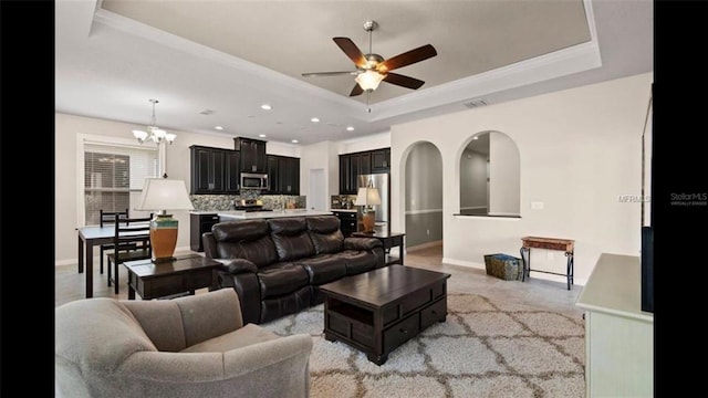 living area with visible vents, ceiling fan with notable chandelier, a tray ceiling, recessed lighting, and baseboards