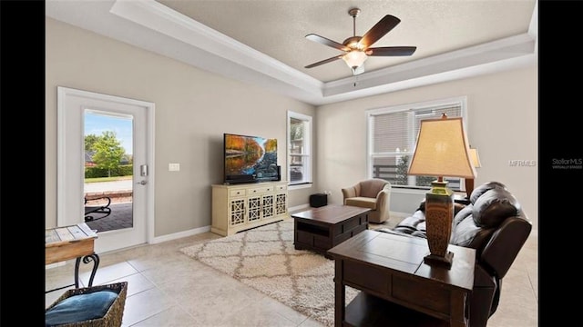 living room with tile patterned flooring, baseboards, a textured ceiling, a raised ceiling, and a ceiling fan