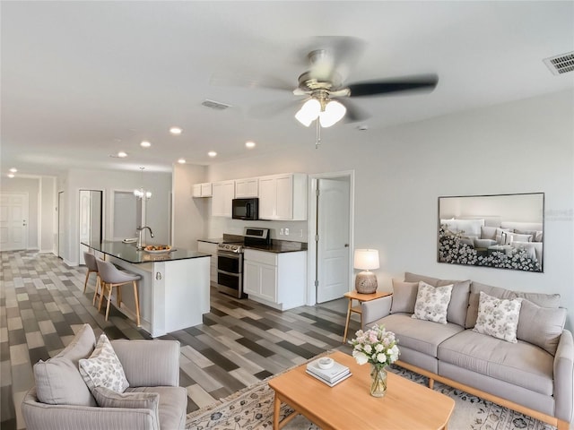 living room featuring recessed lighting, visible vents, carpet, and ceiling fan with notable chandelier