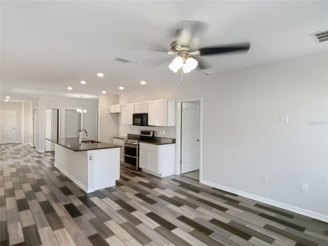 kitchen featuring dark countertops, visible vents, black microwave, and range with two ovens