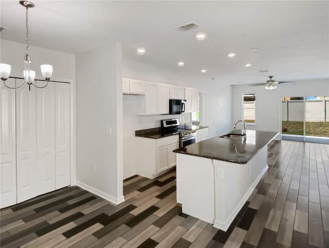 kitchen with dark countertops, visible vents, black microwave, stainless steel range with electric cooktop, and a sink