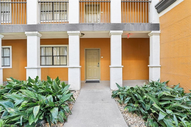 view of exterior entry with stucco siding and a balcony