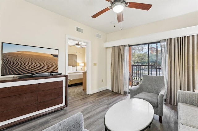 living area with wood finished floors, visible vents, and baseboards