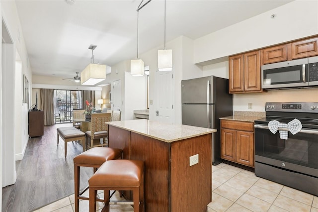 kitchen with hanging light fixtures, brown cabinets, appliances with stainless steel finishes, and a kitchen island