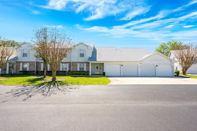 view of front of house featuring a front lawn, brick siding, a garage, and driveway